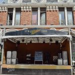Palco de música ao ar livre montado diante de uma fachada histórica ricamente detalhada.