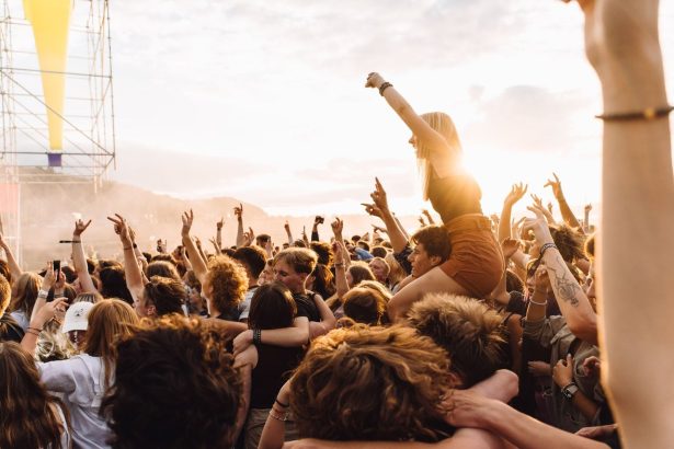 Público reunido em um festival de música ao ar livre durante o pôr do sol.