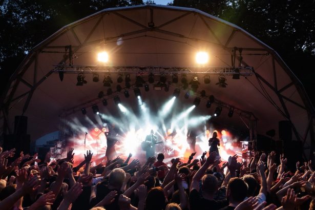 Banda se apresenta em palco ao ar livre diante de um público entusiasmado durante um festival de música.