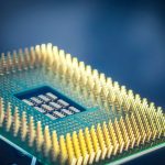Close de um chip de computador com pinos dourados sobre fundo azul.